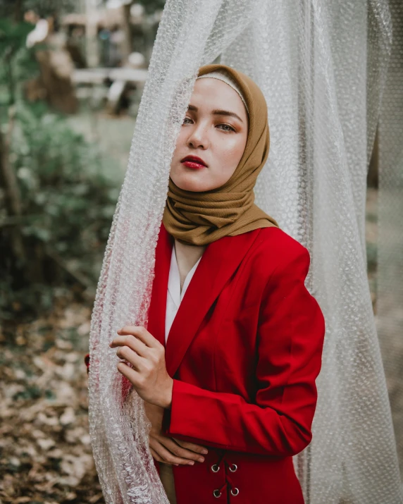 a woman wearing a red coat and a scarf, a colorized photo, trending on pexels, sumatraism, wearing suit, photoshoot for skincare brand, veiled face, queer woman