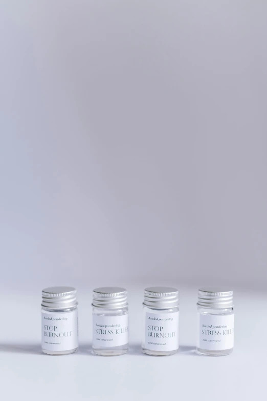 four small jars with white labels sitting on a white surface, inspired by Cerith Wyn Evans, unsplash, product studio lighting, reagents, 3/4 front view, hibernation capsule close-up