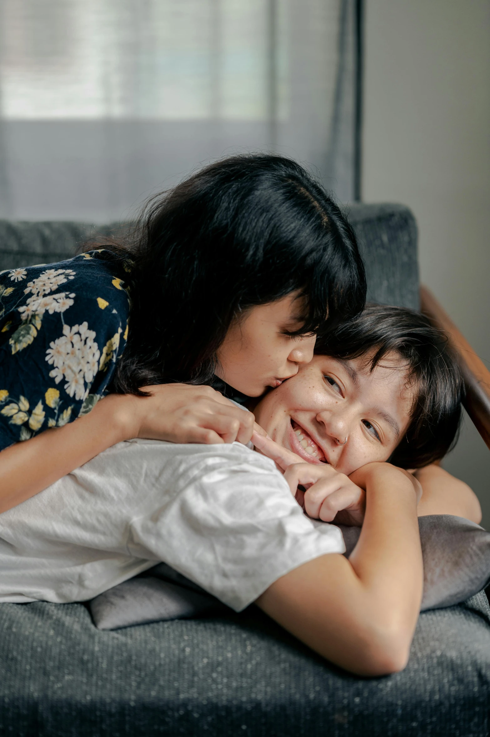 a woman hugging a child on a couch, pexels contest winner, asian female, lesbian kiss, promo image, multiple stories