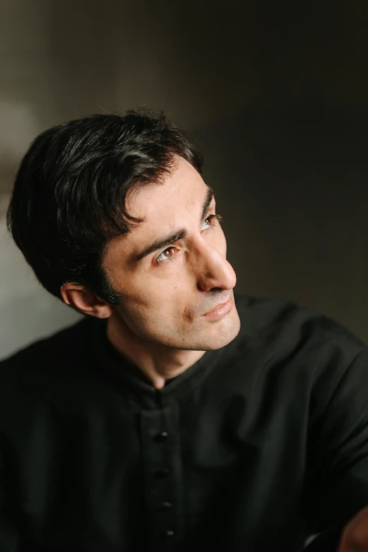 a man sitting at a table with a remote in his hand, an album cover, inspired by Federico Zandomeneghi, a handsome man，black short hair, headshot profile picture, colin greenwood (bass), classical