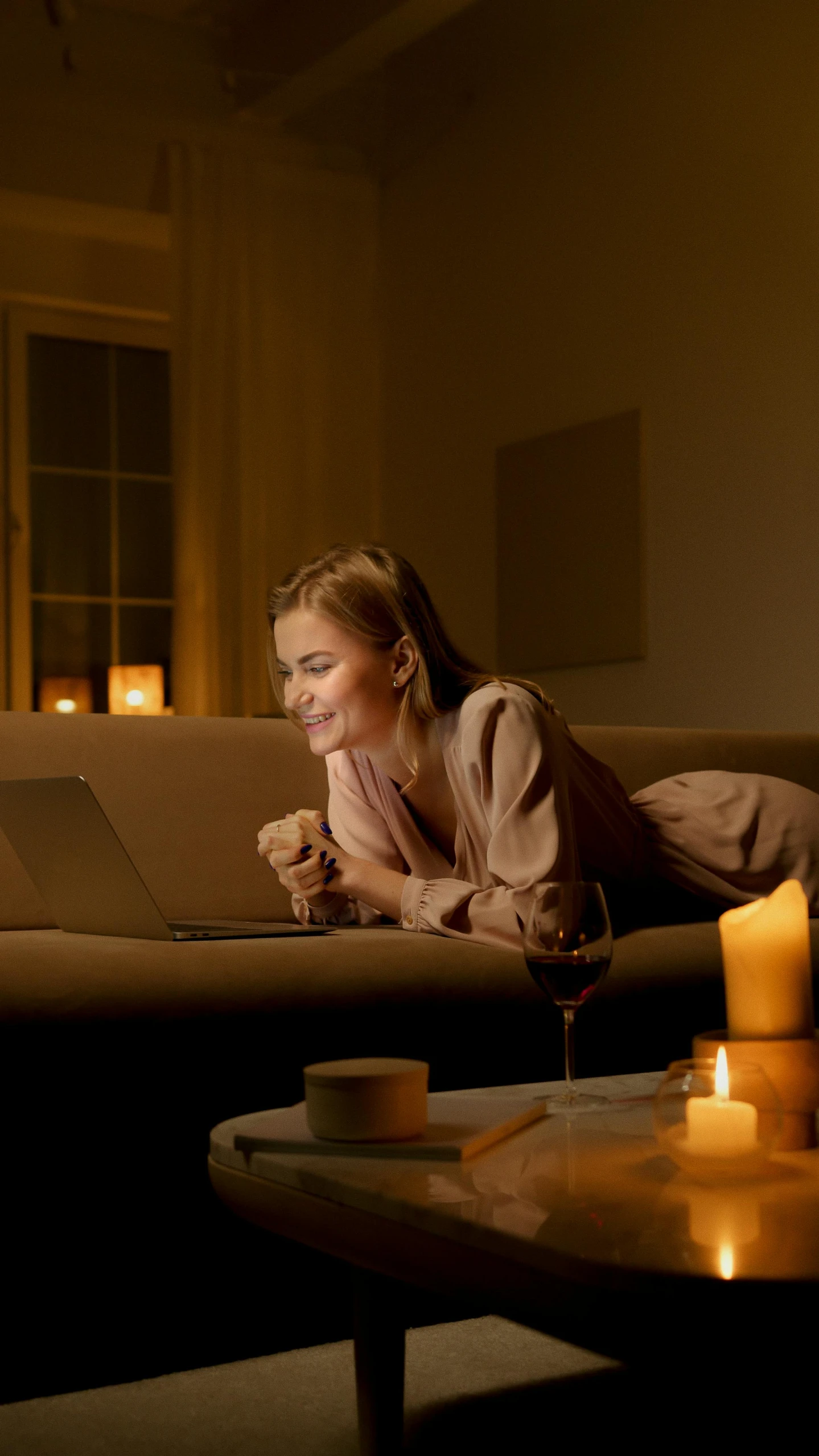 a woman laying on a couch using a laptop, by Jesper Knudsen, pexels, romanticism, cozy candlelight, a still of a happy, calmly conversing 8k, high quality photo