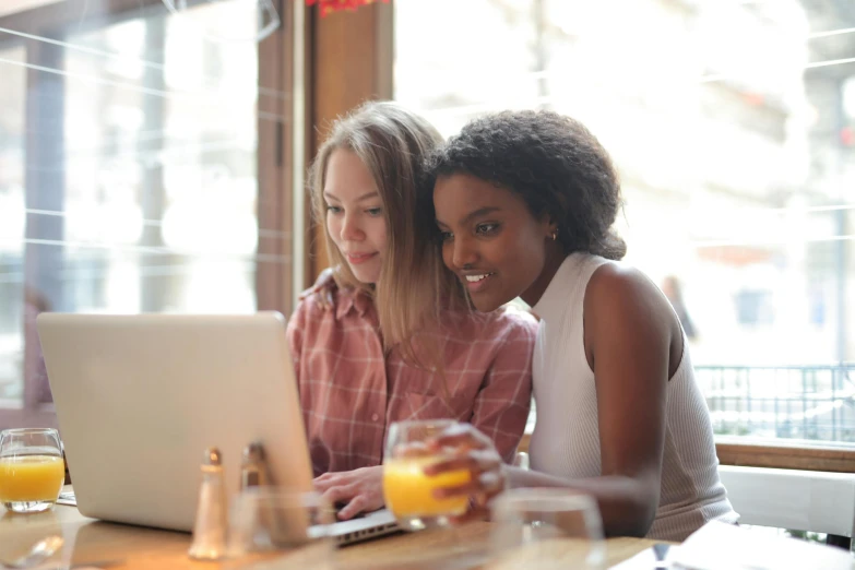 two women sitting at a table looking at a laptop, trending on pexels, profile pic, brown, stacked image, high quality image