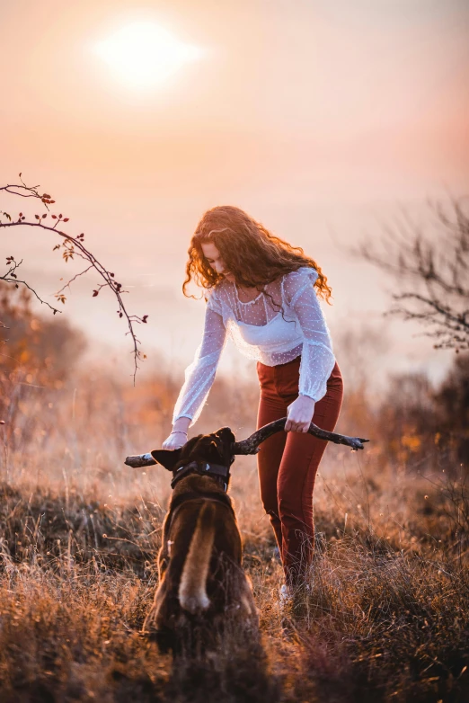 a woman playing with a dog in a field, by Adam Marczyński, pexels contest winner, romanticism, handsome girl, at sunset in autumn, with a long, australian