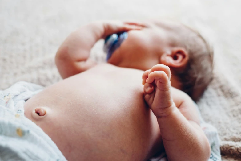 a close up of a baby laying on a blanket, by Will Ellis, trending on pexels, nipple, blue, holding an epée, lachlan bailey