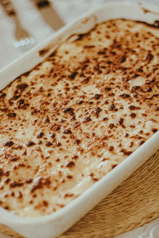 a casserole dish sitting on top of a table, by Lee Loughridge, unsplash, white with chocolate brown spots, lasagna, fine texture detail, maple syrup sea