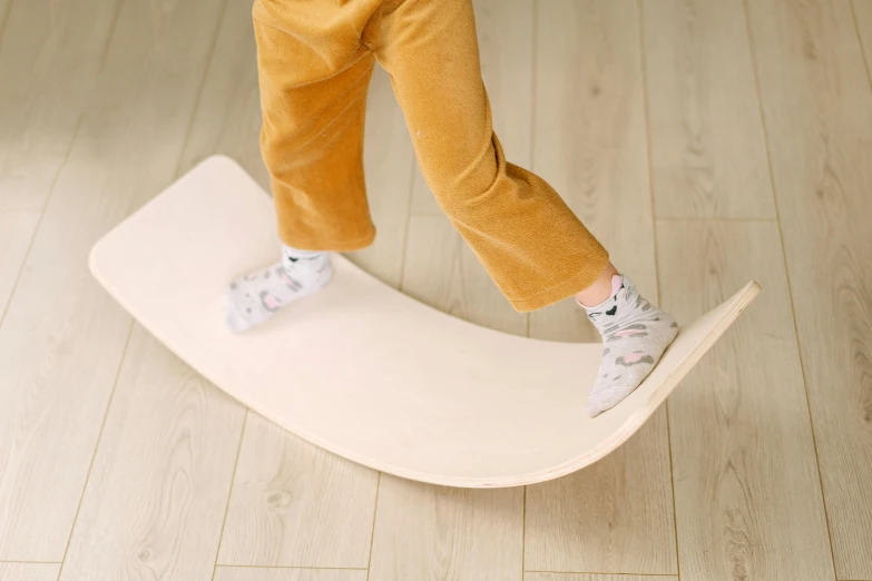 a person standing on a skateboard on a wooden floor, inspired by Sarah Lucas, trending on pexels, toddler, curved furniture, activity play centre, white finish