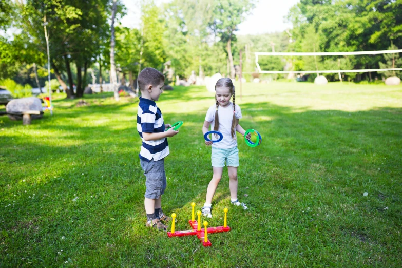 a couple of kids standing on top of a lush green field, dribble contest winner, children's toy, red and yellow scheme, badminton, outside