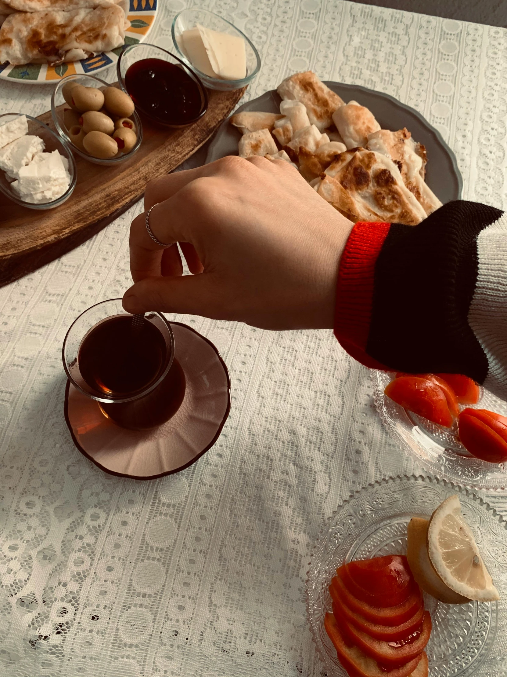 a table topped with plates of food and glasses of wine, a colorized photo, inspired by Louis Stettner, leather cuffs around wrists, aykut aydogdu, cropped wide sleeve, red sweatband
