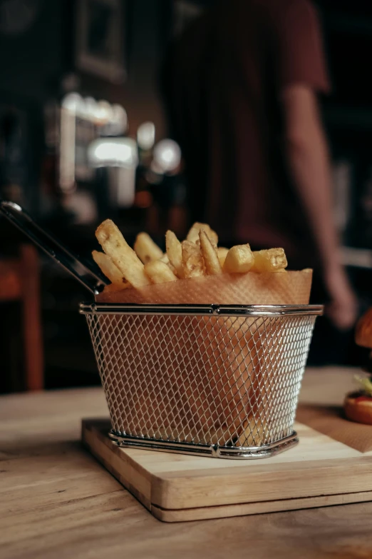 a basket of fries sitting on top of a wooden table, a picture, 2019 trending photo, stainless steel, restaurant, crisp details