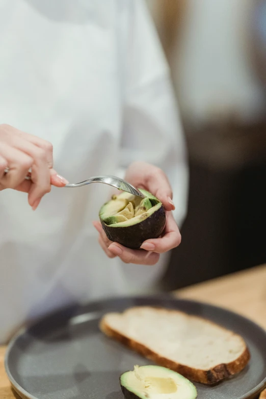 a person holding a spoon over a plate of food, avocado, mortar and pestle, plating, subtle wear - and - tear