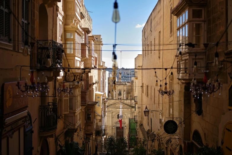 a street filled with lots of tall buildings, a photo, pexels contest winner, renaissance, wrought iron architecture, bathed in light, middle eastern details, wires hanging above street