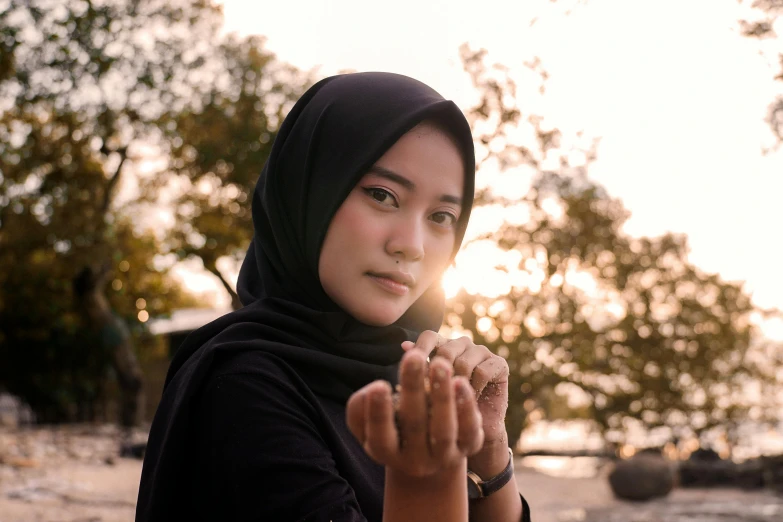 a woman standing on a beach with her hands in the air, a picture, by Bernardino Mei, pexels contest winner, hurufiyya, close up potrait, islamic, avatar image, handsome girl