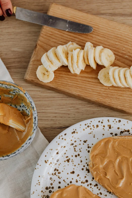 a white plate topped with peanut butter and sliced bananas, a picture, inspired by Richmond Barthé, trending on pexels, on a wooden desk, speckled, navy, manuka