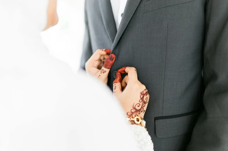 a close up of a person wearing a suit and tie, by Julia Pishtar, hurufiyya, couple, orientalisme, touching her clothes, silver white red details