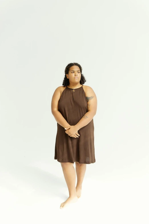 a woman in a brown dress posing for a picture, by Jessie Algie, unsplash, overweight, on clear background, photographed for reuters, light-brown skin