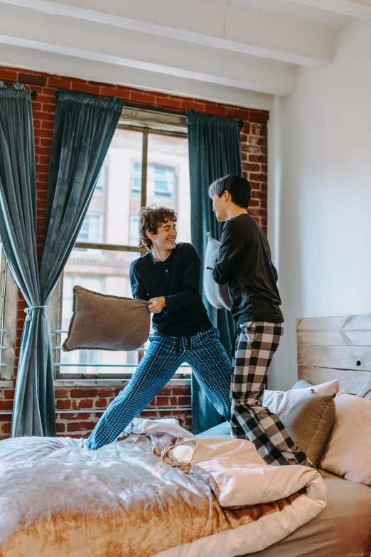 a couple of people standing on top of a bed, doing a kick, san francisco, head bent back in laughter, non-binary