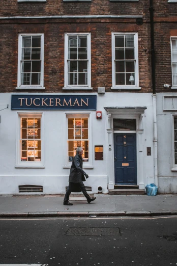 a man walking down the street in front of a building, inspired by Murray Tinkelman, stuckism, shop front, tudor, 2019 trending photo, quackery