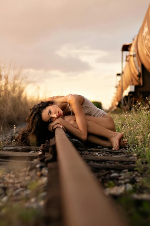 a woman laying on a train track next to a train, a portrait, by Brian Thomas, unsplash contest winner, amazing beauty, contorted, yard, soft glow