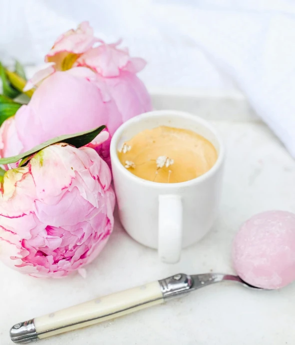 a white plate topped with pink flowers next to a cup of coffee, ice cream, white marble interior photograph, covered with pink marzipan, cervix awakening