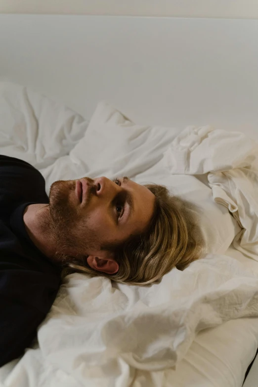 a man laying on top of a bed covered in white sheets, an album cover, trending on pexels, hyperrealism, long swept back blond hair, felix englund style, sleepy fashion model face, gif