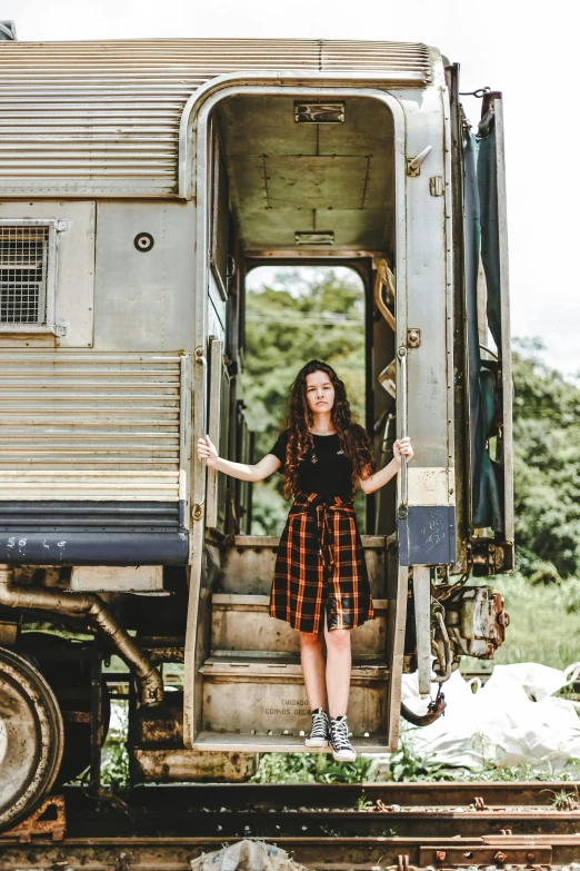 a woman standing in the doorway of a train car, a portrait, pexels contest winner, plaid skirt, avatar image, outdoor photo, kaya scodelario