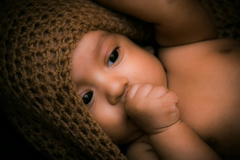 a close up of a baby wearing a knitted hat, an album cover, inspired by Anne Geddes, shutterstock contest winner, fantastic realism, ( brown skin ), brown, portrait shot 8 k, a handsome