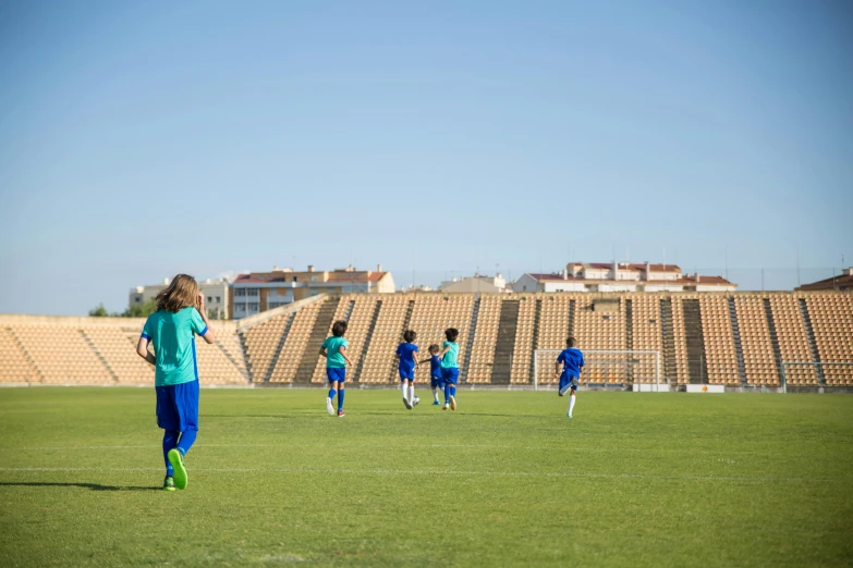 a group of young people playing a game of soccer, by Carlo Martini, unsplash, conceptual art, costa blanca, schools, stadium setting, wearing a school soccer uniform