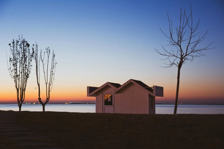 a house sitting on top of a beach next to a body of water, pexels contest winner, postminimalism, warm glow from the lights, shed, minimalist photorealist, tiny house