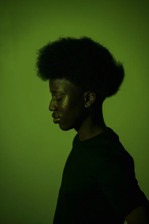 a woman standing in front of a green wall, inspired by Carrie Mae Weems, pexels contest winner, afrofuturism, portrait of 1 5 - year - old boy, moody evening light, silhouette of man, natural hair