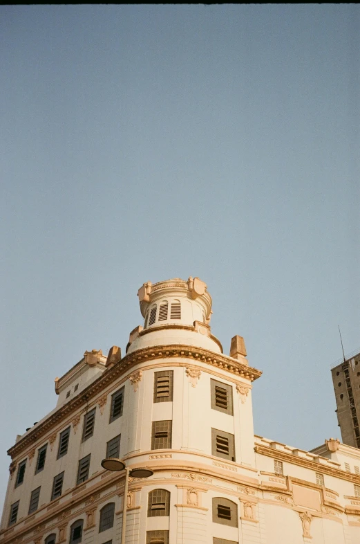 a tall building with a clock on top of it, inspired by Manuel Franquelo, neoclassicism, at golden hour, rounded roof, location ( favela ), taken with kodak portra