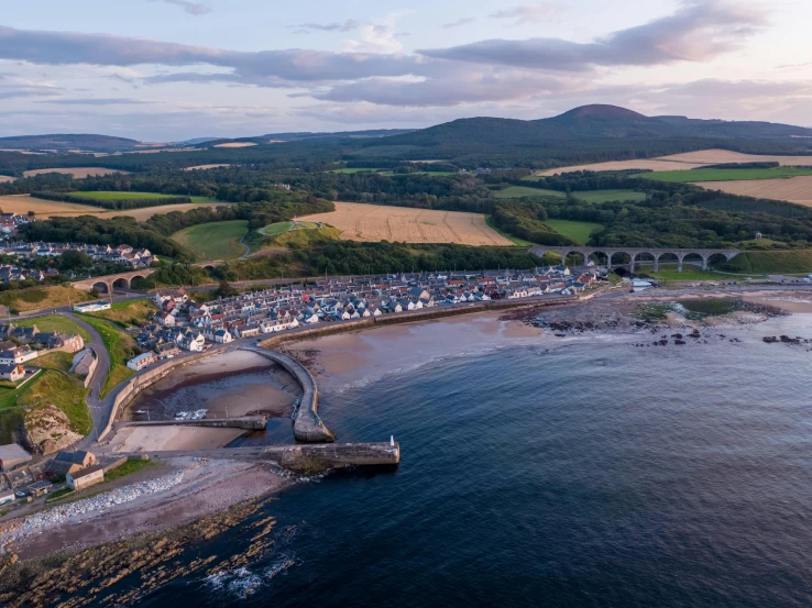 a large body of water next to a beach, by Julian Allen, pexels contest winner, happening, dunwall city, small port village, aerial, summer evening