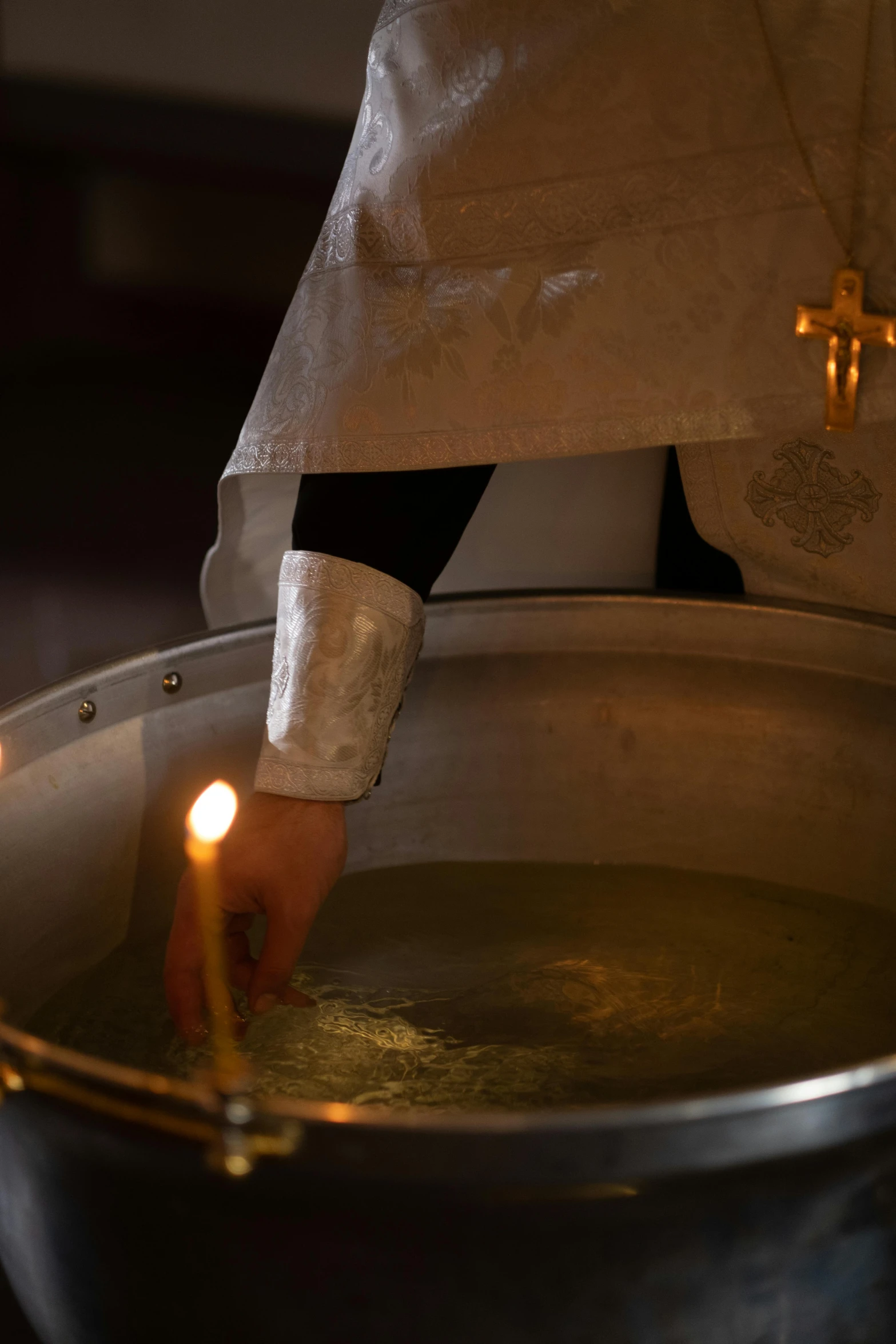 a person holding a lit candle in a pot of water, wearing robes of silver, filling with water, high quality photo, in a sanctuary