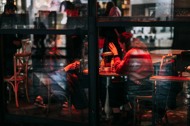 a group of people sitting at a table in a restaurant, a photo, by Emma Andijewska, pexels contest winner, looking through frosted glass, it's raining outside, night outside, people at work