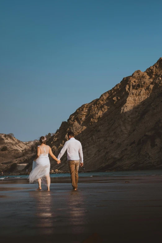 a man and a woman walking on a beach, a photo, pexels contest winner, oman, bride and groom, golden bay new zealand, cliffs