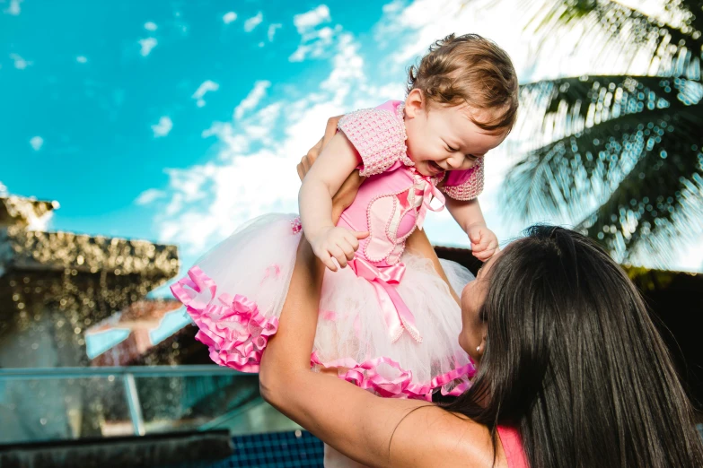 a woman holding a baby in her arms, pexels contest winner, happening, wearing a pink tutu, avatar image, having fun in the sun, 3 5 year brazilian mother