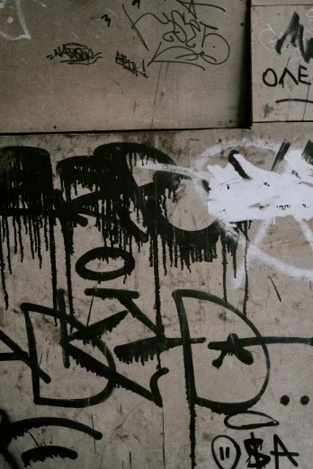 a wall covered in lots of graffiti next to a fire hydrant, unsplash, grainy picture, dripping black and grey paint, tag, scratched photo