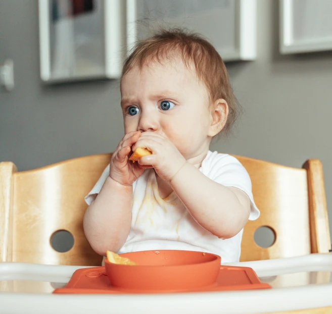 a baby sitting in a high chair eating food, by Emma Andijewska, pexels contest winner, eating garlic bread, square, pout, 1 2 9 7