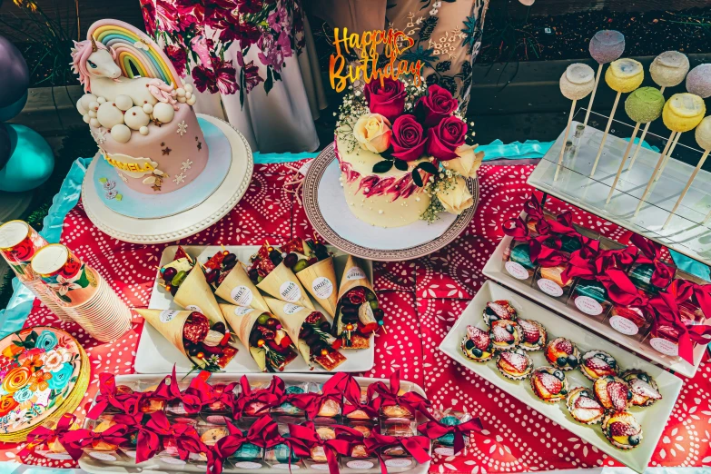 a table topped with lots of cakes and desserts, by Julia Pishtar, unsplash, colorful with red hues, birthday cake on the ground, flowers, background image