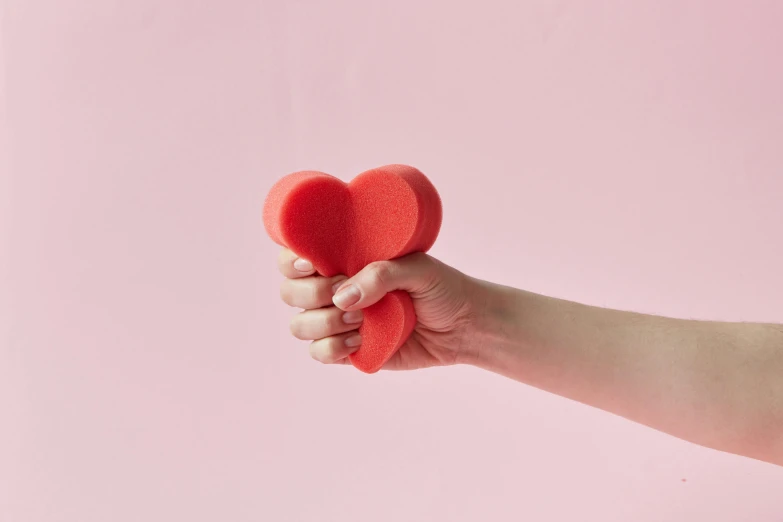 a person holding a red heart in their hand, inspired by Louise Bourgeois, foam, soft volume absorbation, official product photo, coral red