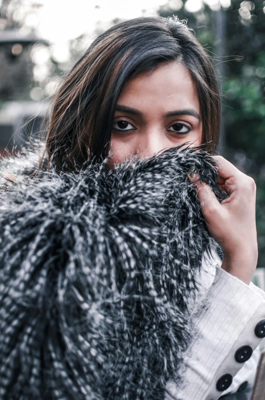 a woman covering her face with a furry coat, shot with premium dslr camera, portrait of ana de armas, textures, grey