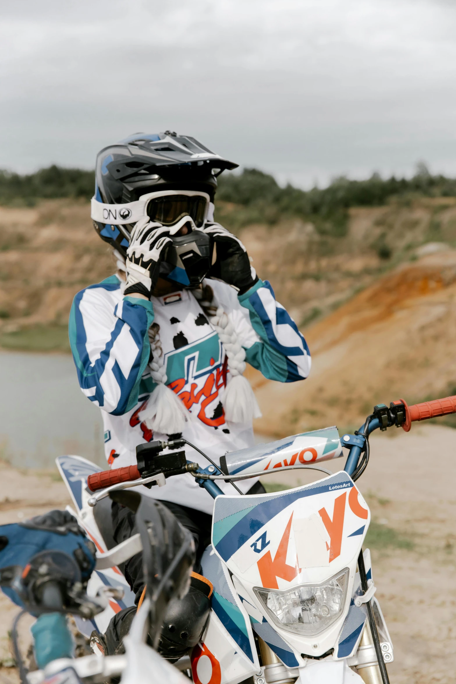 a man riding on the back of a dirt bike, unsplash, photorealism, costume with blue accents, taking a picture, sports, white