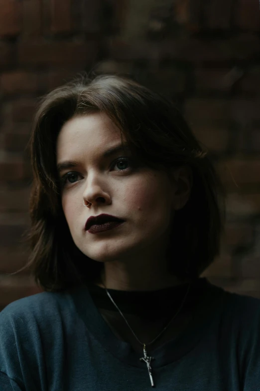 a woman standing in front of a brick wall, an album cover, inspired by Elsa Bleda, pexels contest winner, renaissance, faint smile dark lipstick, headshot profile picture, wearing a dark sweater, loish |