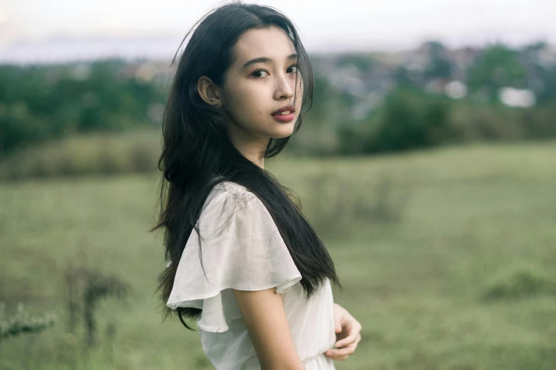 a woman standing on top of a lush green field, inspired by Tang Yifen, pexels contest winner, thin lustrous long dark hair, portrait of a japanese teen, ethnicity : japanese, sydney park