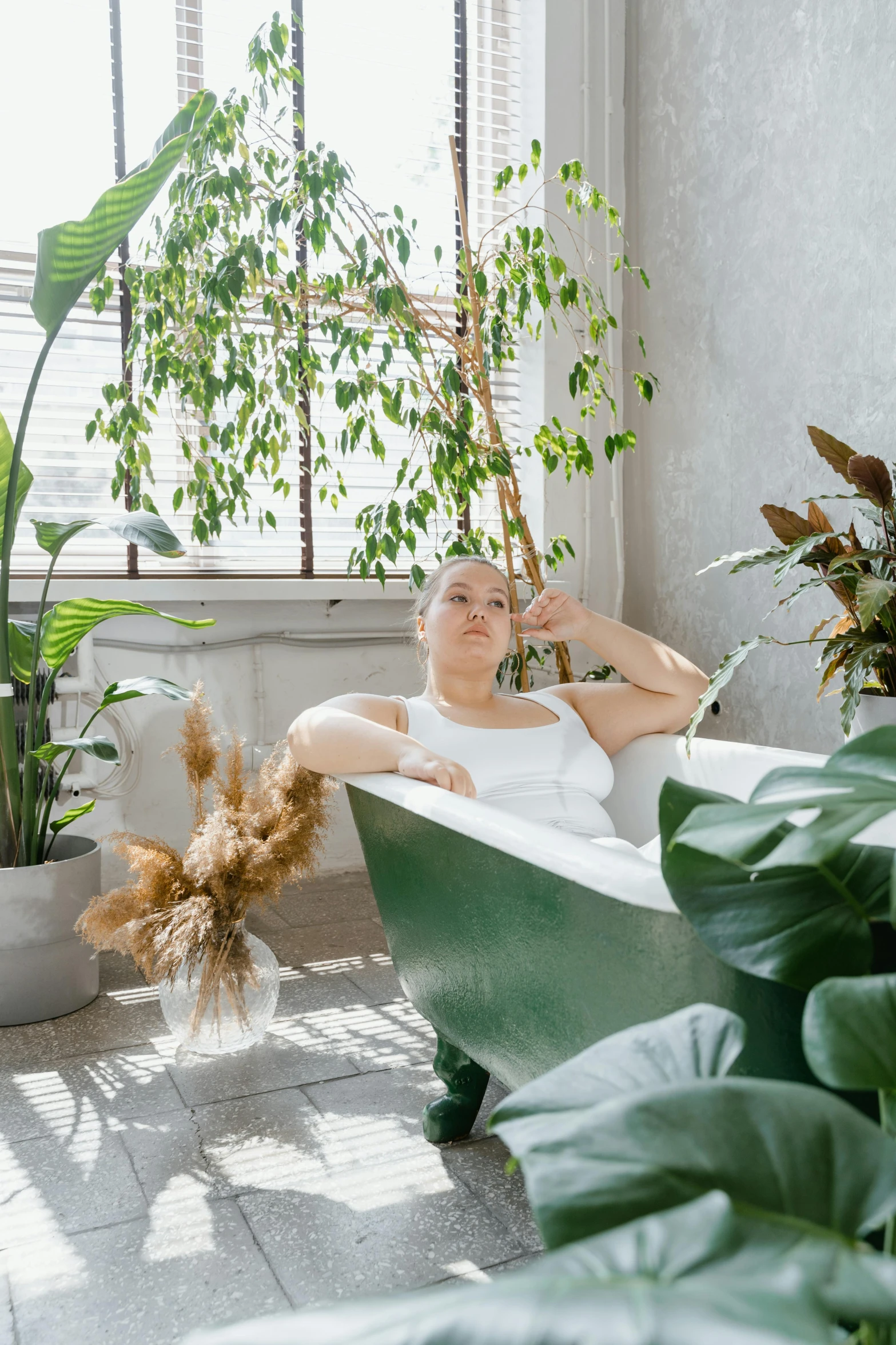 a woman sitting in a bathtub surrounded by plants, inspired by Elsa Bleda, trending on unsplash, alluring plus sized model, on a bright day, sitting on a couch, aurora aksnes