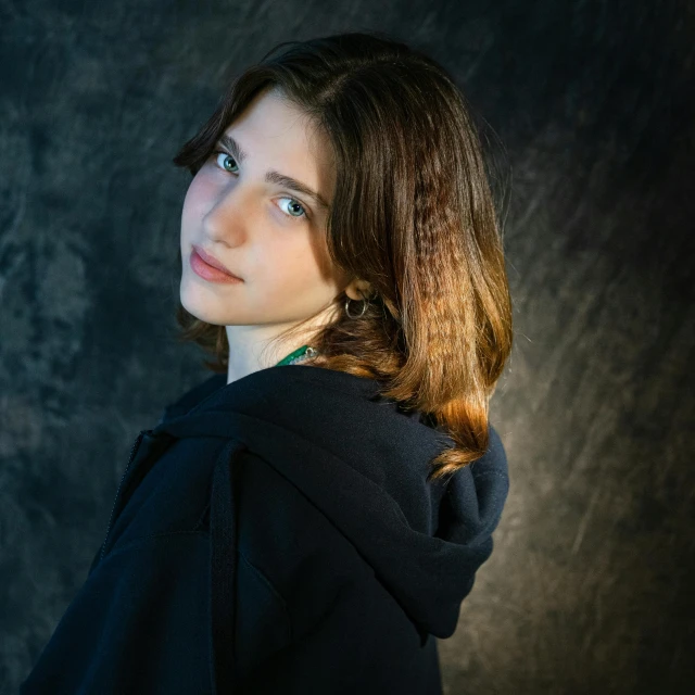 a woman in a black hoodie posing for a picture, inspired by Anna Füssli, pexels contest winner, photorealism, natalia dyer, shoulder-length brown hair, a young female wizard, professional studio photograph