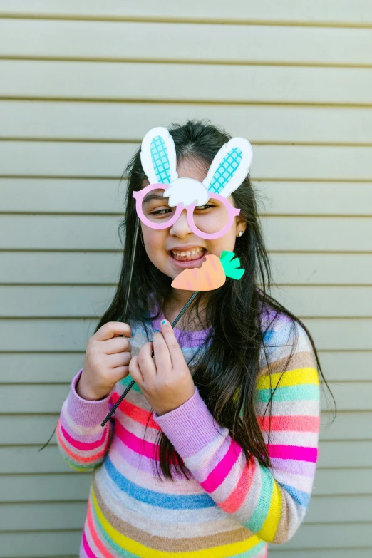 a young girl wearing bunny ears and holding a piece of paper in front of her face, implanted sunglasses, blippi, portrait n - 9, multi - coloured