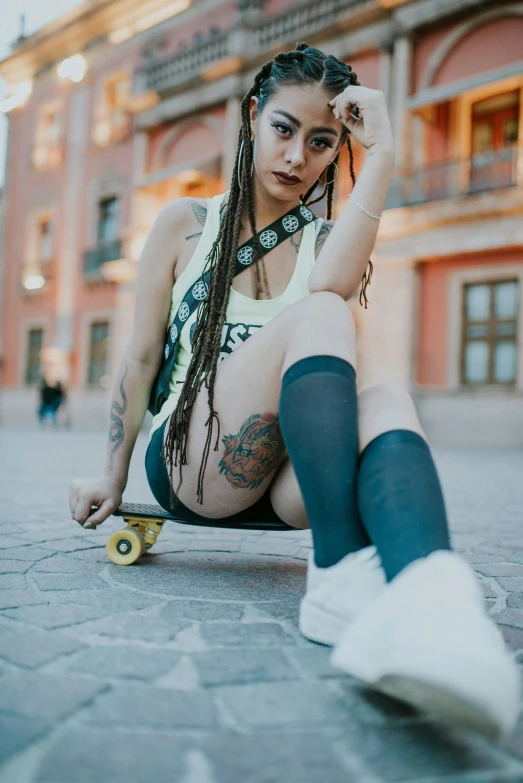 a woman sitting on a skateboard in front of a building, with black pigtails, daisy dukes, tlaquepaque, portrait featured on unsplash