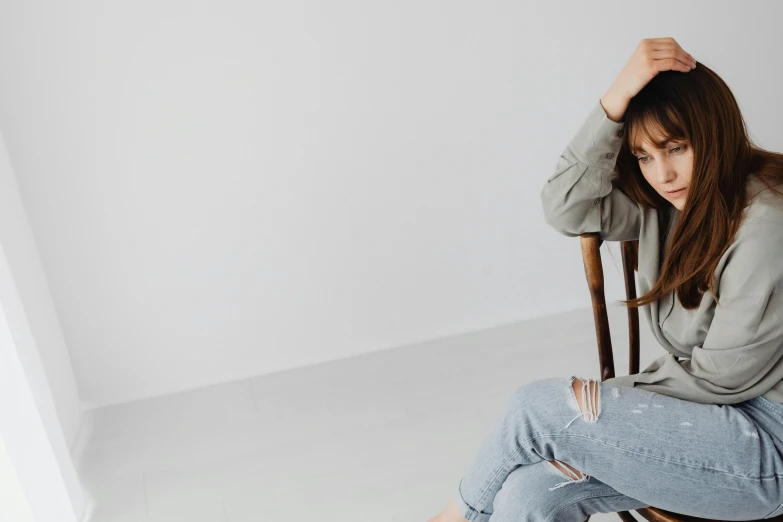 a woman sitting on top of a wooden chair, trending on pexels, grey, woman holding another woman, background image, young asian girl