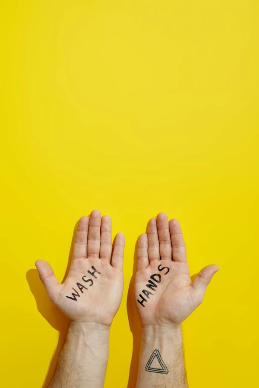 a person holding their hands up with words written on them, an album cover, by Gavin Hamilton, trending on pexels, yellow, wash, hands crossed, warts