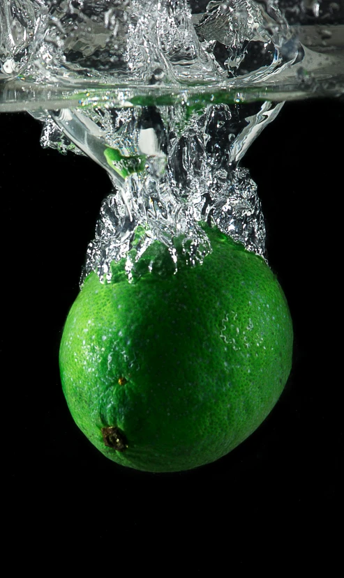 a lime falling into the water with a black background, by Dave Allsop, ((still life)), head exploding, mint, squish